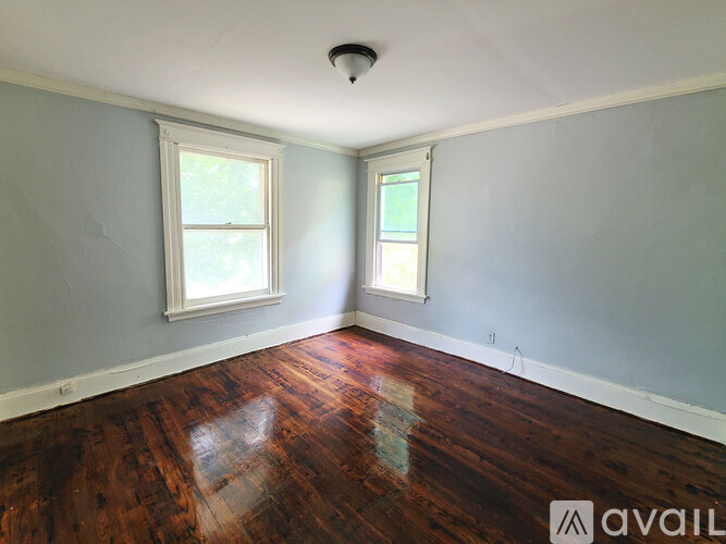 A room with wooden floors and two windows.
