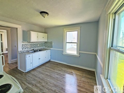 A kitchen with a white stove top oven and white cabinets.