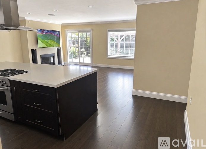A modern kitchen with a flat screen TV mounted above the island.