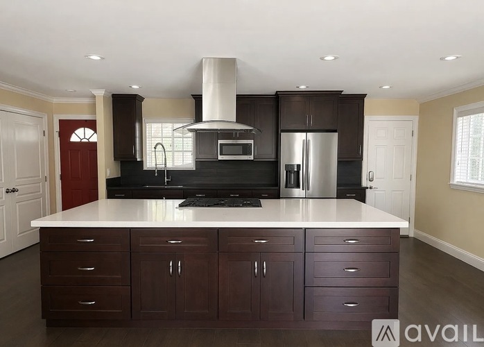 A kitchen with dark brown cabinets and a white island.