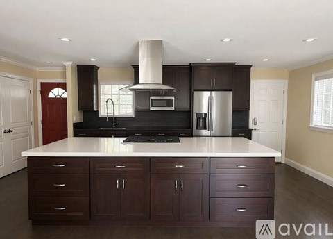 A kitchen with dark brown cabinets and a white island.