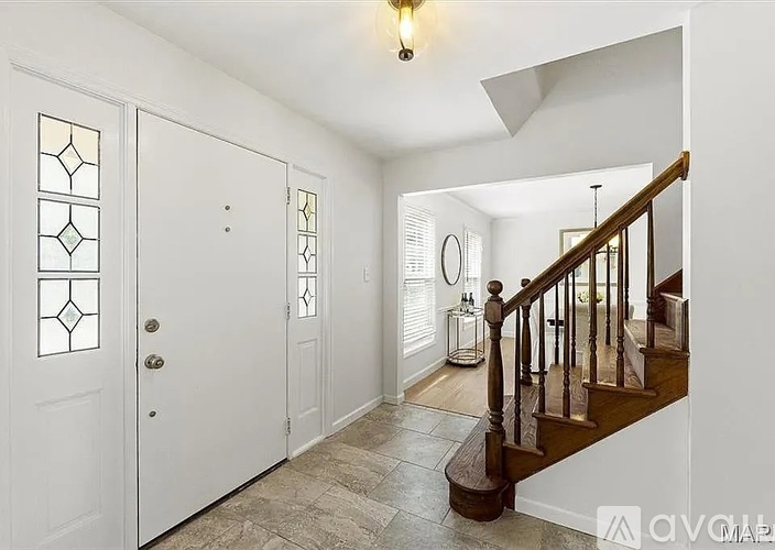 A hallway with a staircase and a door with a glass panel.