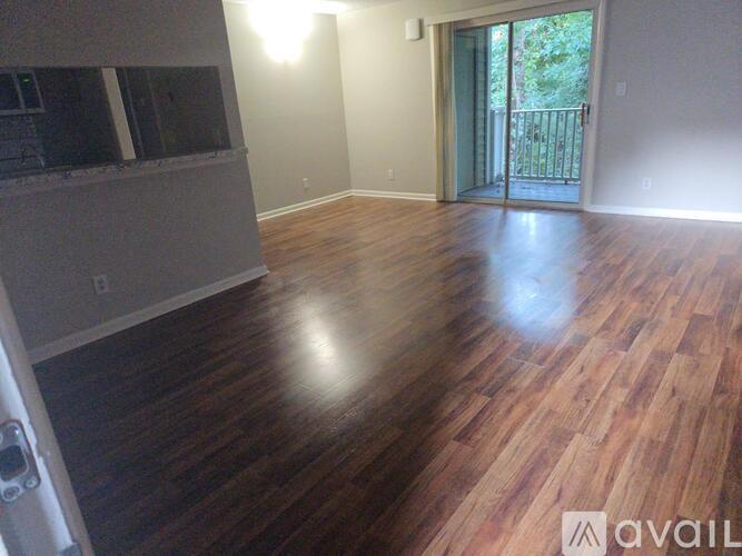 A room with wooden flooring and a sliding glass door leading to a balcony.