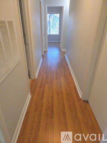 A long hallway with wooden floors and white walls.