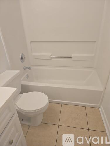 A white toilet sits next to a bathtub in a bathroom.