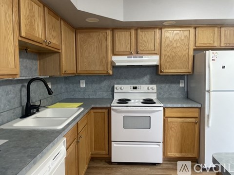 A kitchen with wooden cabinets and a white stove top oven.