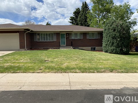 A house with a green lawn and trees in the background.