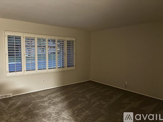 A room with a window covered by white blinds.