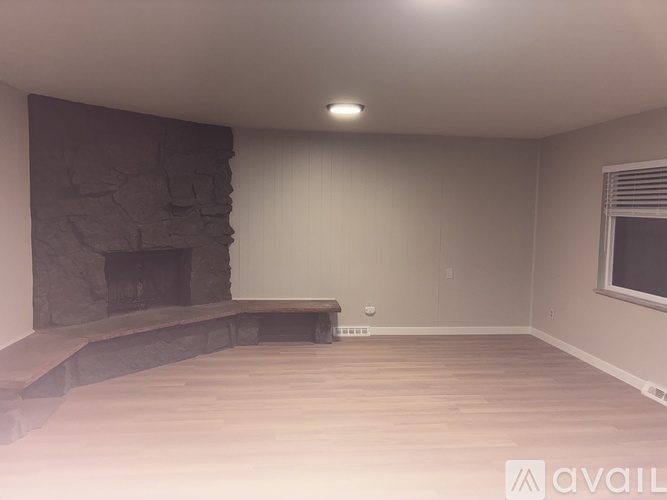A room with a stone fireplace and wooden flooring.