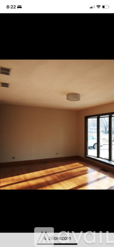 A room with a wooden floor and a window letting in sunlight.