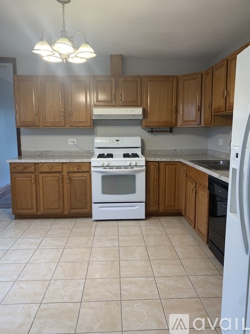 A kitchen with a white stove top oven and white refrigerator.