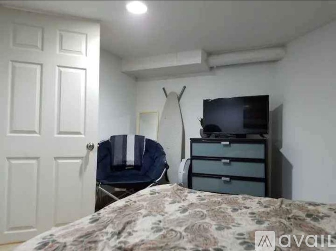 A bedroom with a bed, a chair, and a dresser with a TV on top.