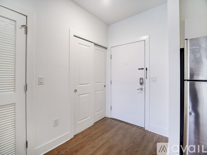 A kitchen with white walls and a wooden floor.