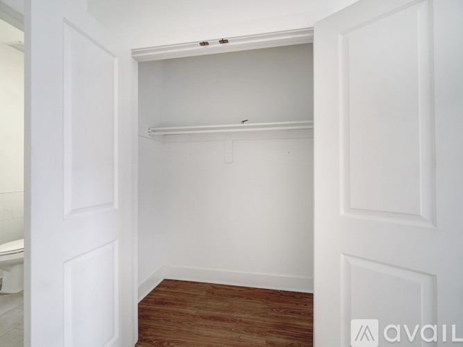 A white door is open to a room with a wooden floor.