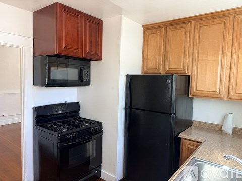 A black refrigerator sits next to a black stove in a kitchen.