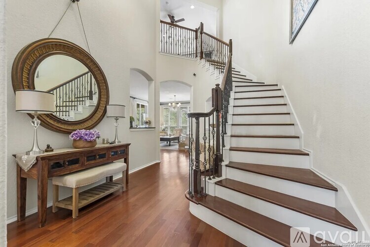 A staircase with a wooden banister and a round mirror above a table with a bench.