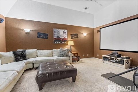 A living room with a white couch and a brown ottoman.