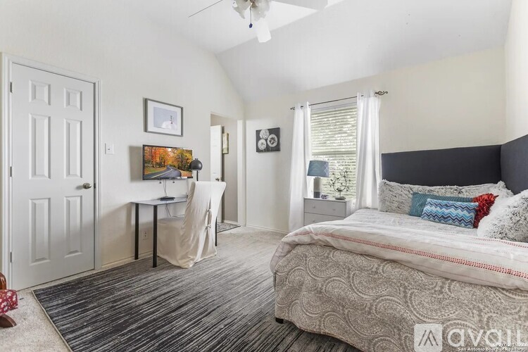 A bedroom with a large bed and a desk with a chair.