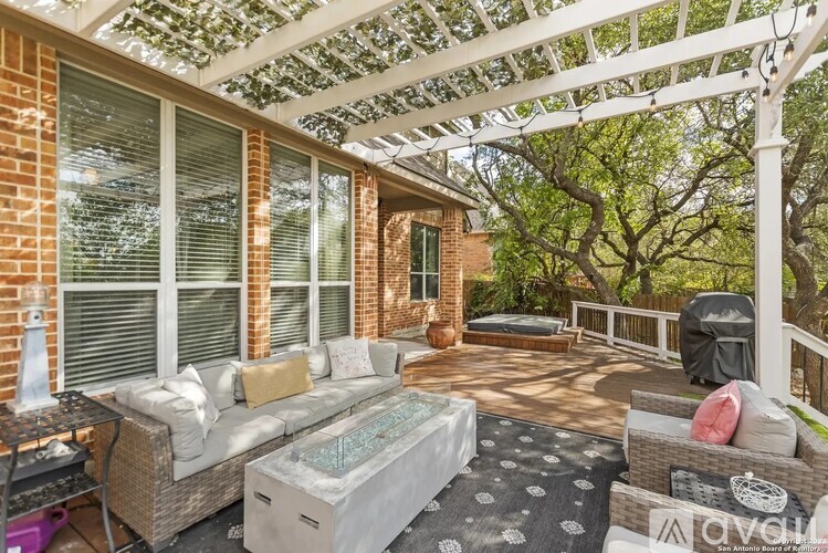 A patio with a white pergola and a hot tub.