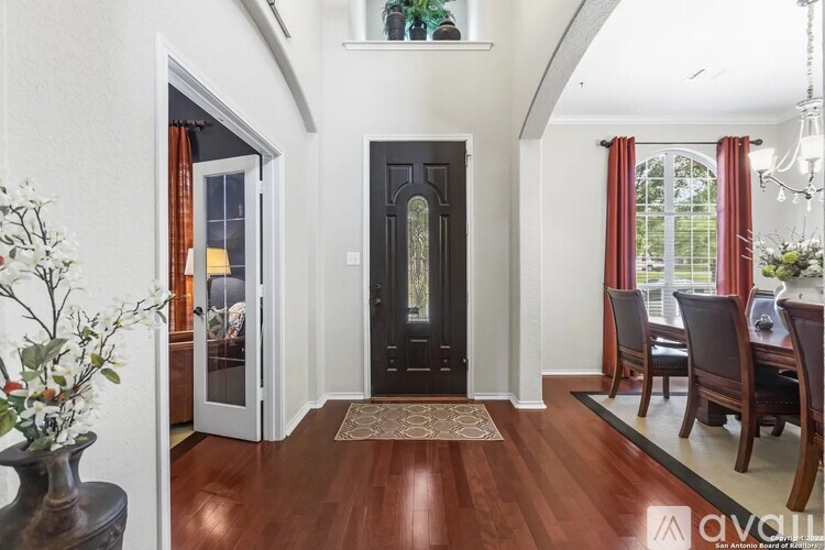 A hallway with a black door and a rug on the floor.
