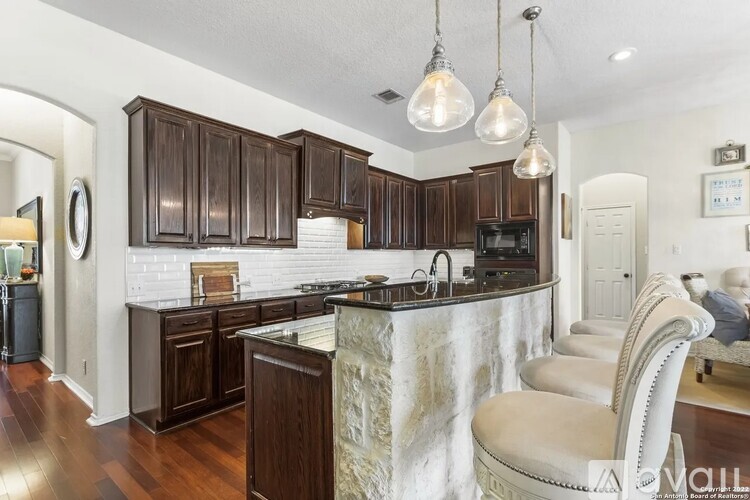 A kitchen with dark wood cabinets and a white brick backsplash.