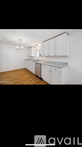 A kitchen with white cabinets and a wooden floor.