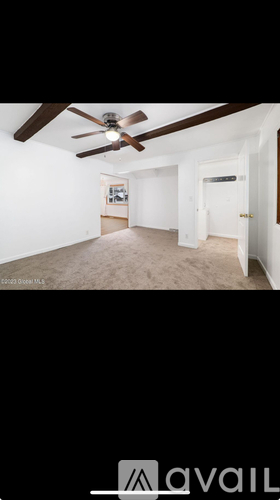 A room with a ceiling fan and carpeted floor.