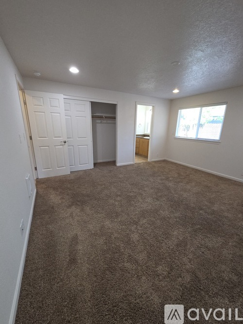 A carpeted room with a door and a window.