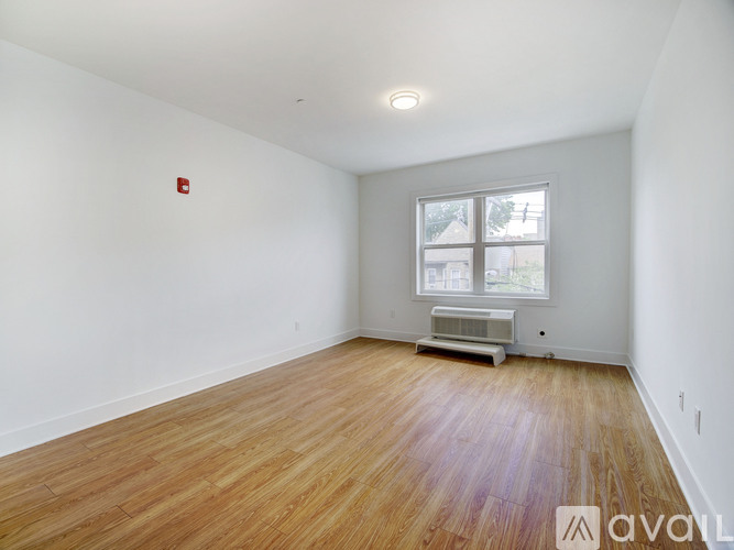 A room with wooden flooring and a window with blinds.