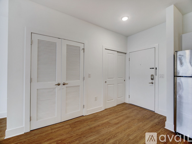 A white room with wooden floors and three doors.