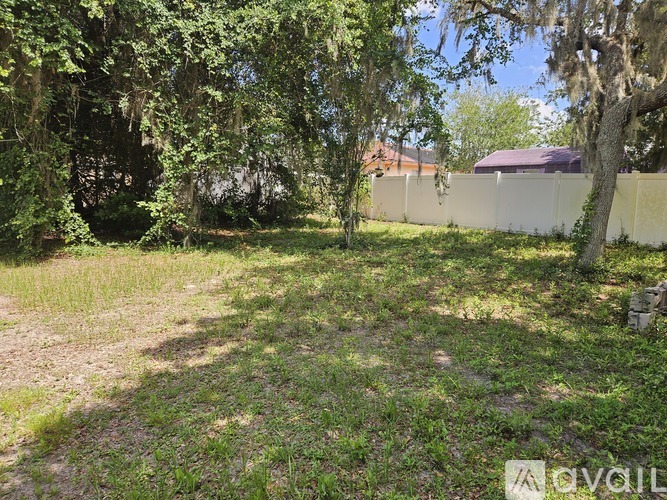 A backyard with a white fence and trees.