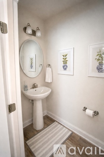 A bathroom with a white pedestal sink and a round mirror.