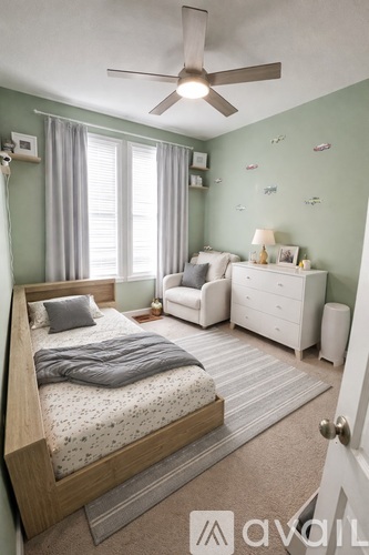 A bedroom with a bed, a couch, a nightstand, and a ceiling fan.