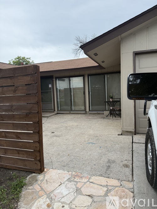 A wooden gate is in front of a house with a car parked in the driveway.