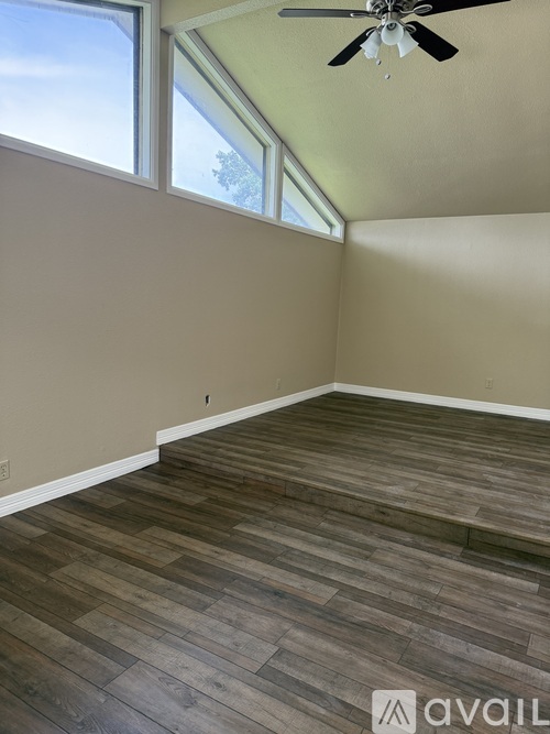 A room with wooden flooring and a ceiling fan.