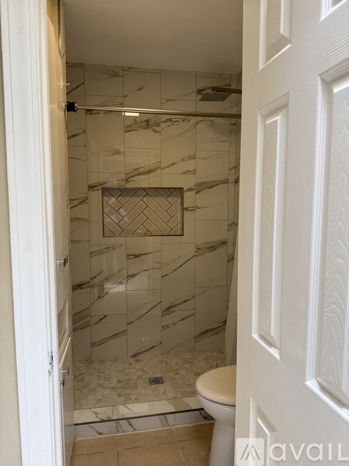 A bathroom with a marble tile shower and toilet.