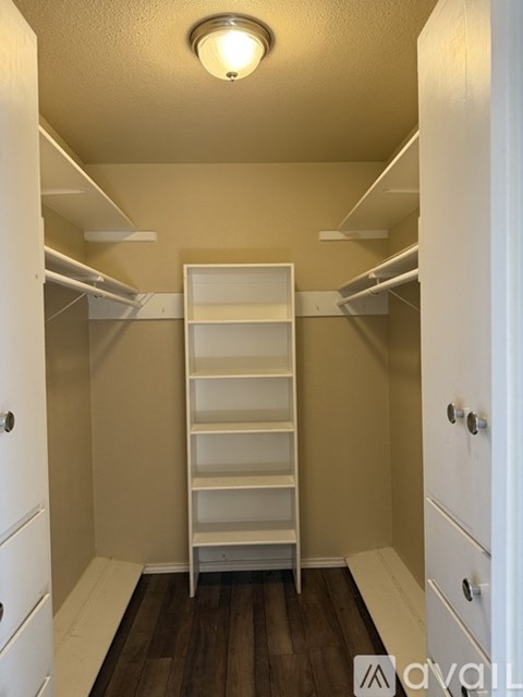 A spacious walk-in closet with white shelves and drawers.