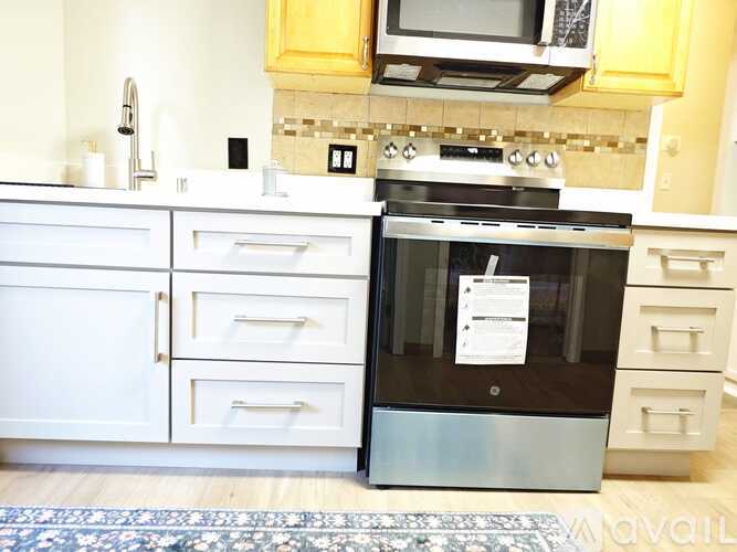 A modern kitchen with a black oven and white cabinets.