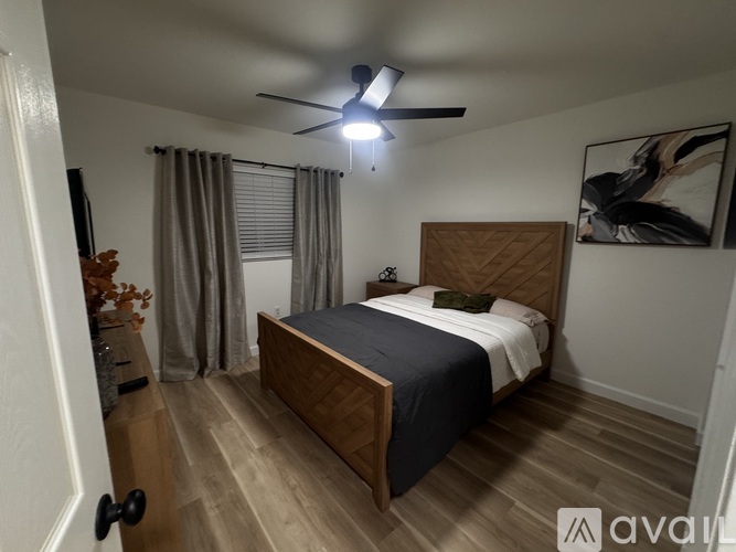 A bedroom with a bed, wooden headboard, and a ceiling fan.