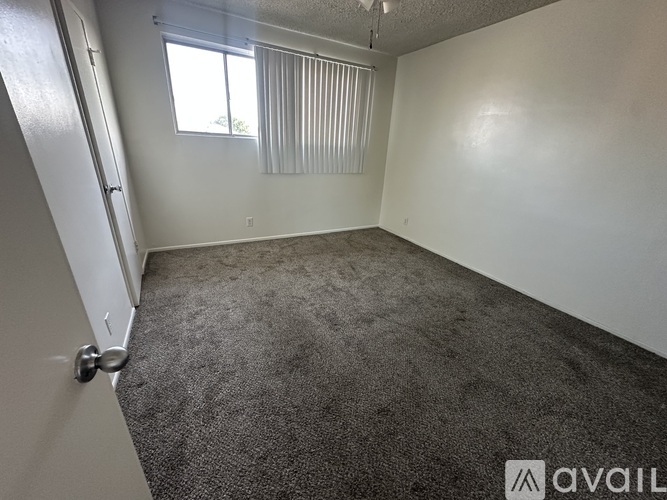 A room with a carpeted floor and a window with blinds.