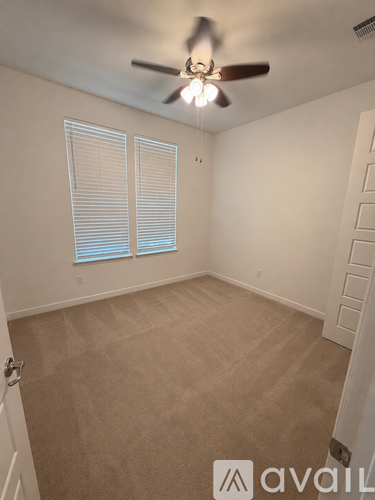 A room with a ceiling fan and carpeted floor.