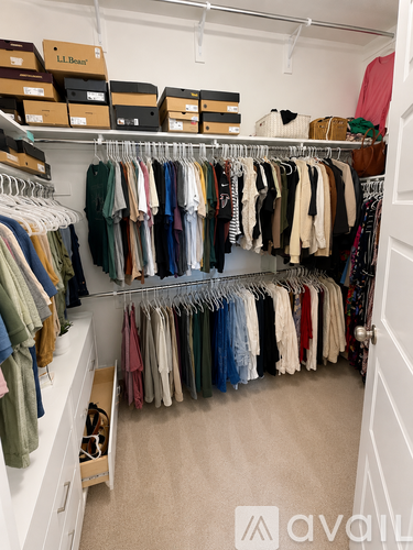 A white closet with clothes hanging on hangers.