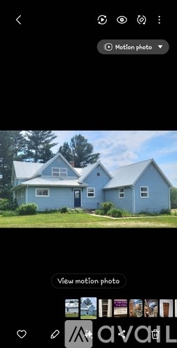 A blue house with a white roof and a tree in front.