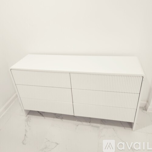 A white cabinet with a grid pattern on the doors is placed on a marble floor.