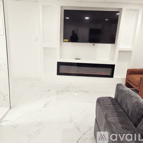A living room with a grey couch and a flat screen TV mounted above a fireplace.
