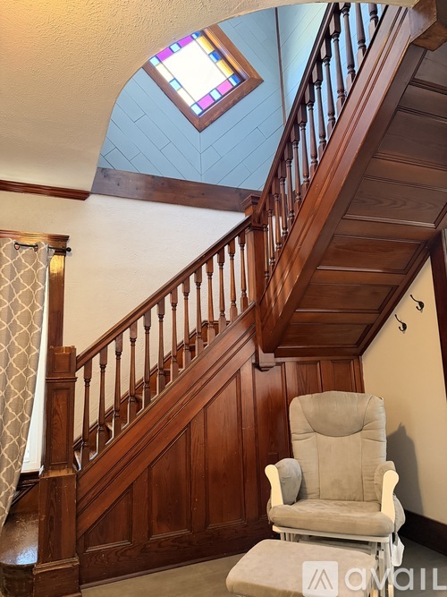 A staircase with a wooden banister and a chair in front of it.