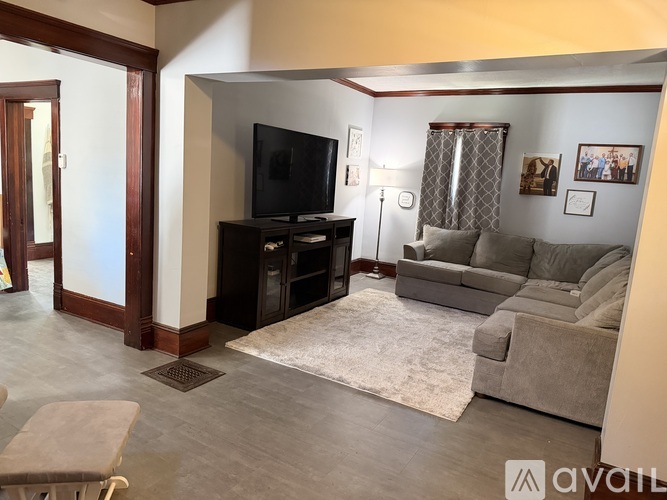 A living room with a grey couch, a television, and a rug.