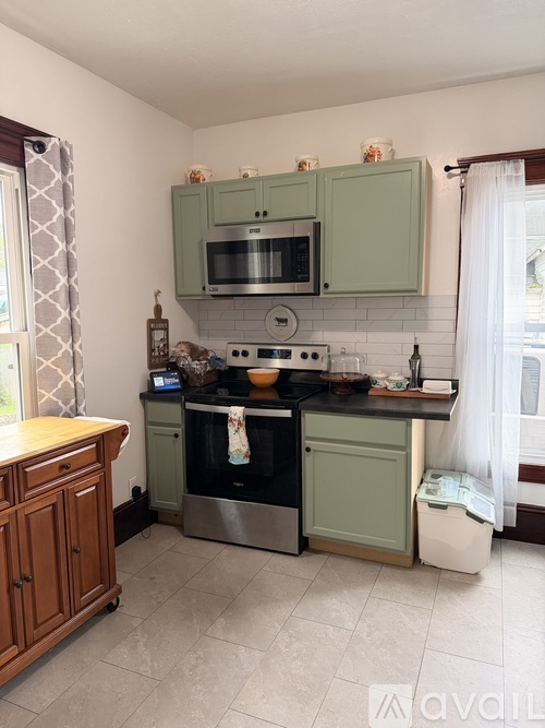 A kitchen with green cabinets and a stainless steel oven.