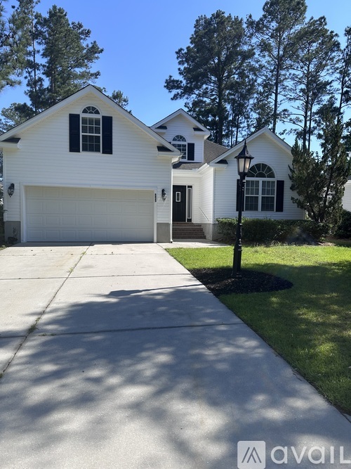 A white house with a black window and a garage door.
