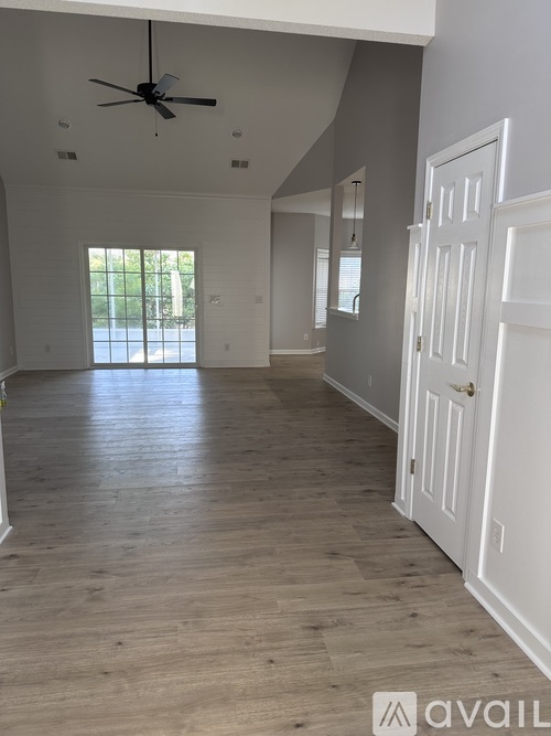 A spacious room with wooden flooring and a ceiling fan.
